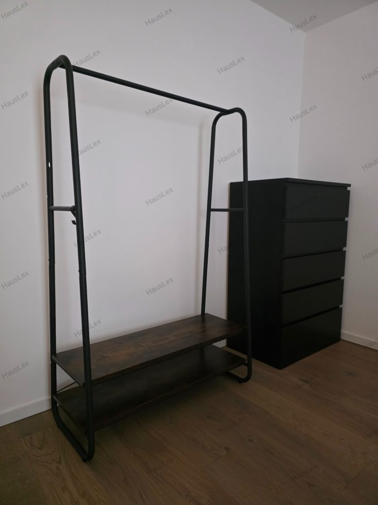 Garderobensystem mit IKEA Kommode (6 Schubladen) – fachgerecht montiert. Offenes Garderobensystem mit Metallrahmen und dunklen Ablageflächen sowie schwarze IKEA Kommode mit sechs Schubladen.